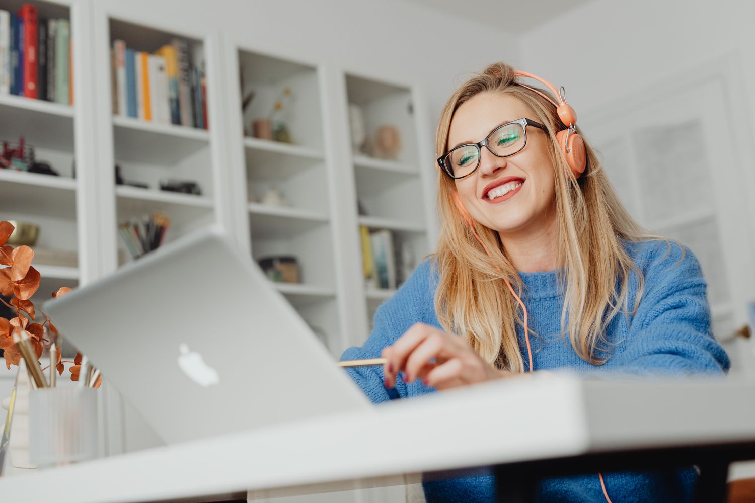 A woman smiling during an online conversation, wearing headphones at her laptop